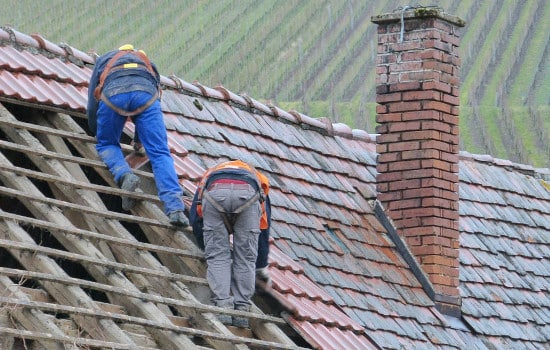 Couvreurs posent des nouvelles tuiles sur le toit d'une maison