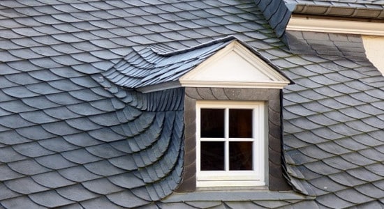 Fenêtre de toit avec avancée sur toiture en ardoise